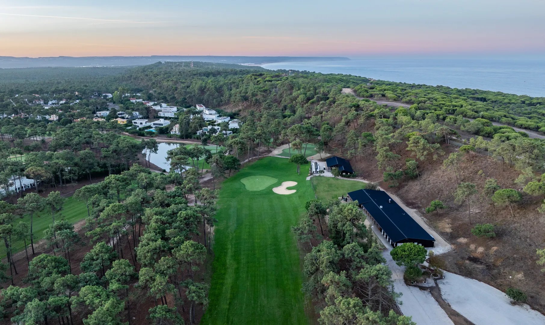 Aerial view of PGA Aroeira — fairways through the pine forests, with the Atlantic beyond